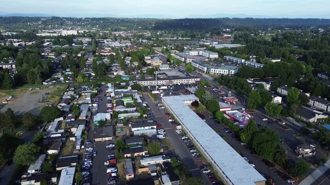 Apartment clusters nestle near dense tree lines adjacent to recreational fields in Kent, WA. Paved lanes weave between multi family units while establishing connections across this valley corridor