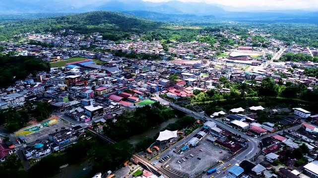 Wide Aerial View of Ecuador Town in Green Valley with River, Hills, Urban Buildings and Tropical South American Landscape Background
