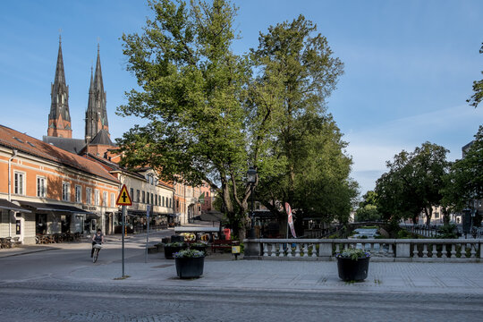 Uppsala Cathedral towers over the city center with shops and trees lining the streets during a clear day in Sweden