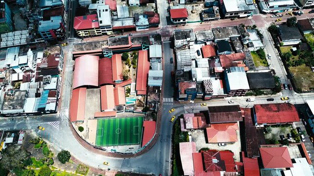 Top Down Drone View of Indoor Sports Court and Urban Blocks in Ecuador Town, Rooftops, Streets and Community Infrastructure Background