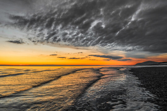 Sunset over the sea at Sandy Gap on Walney Island in Cumbria with view towards Black Combe on August 31, 2020