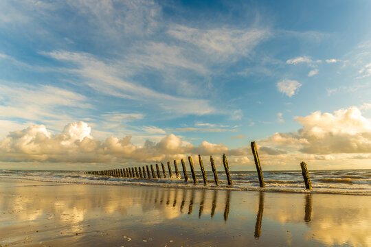 Sunshine and clouds reflect on sand with sea breakers along the shore of Walney Island in the Furness Peninsula