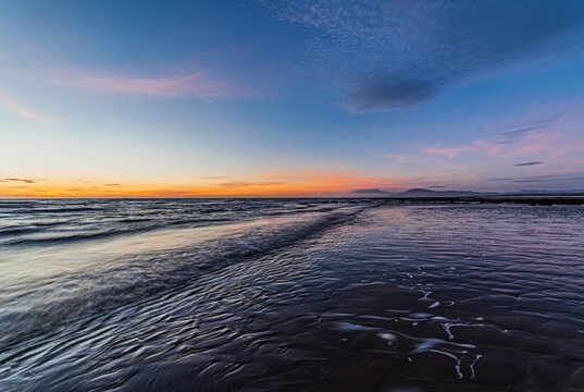Sunset over the waves with Black Combe in the distance from Walney Island along the coast of Cumbria