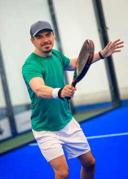 Padel player on the padel court with padel racket and ball in action. Open social tour template. Padel tennis player indoors.