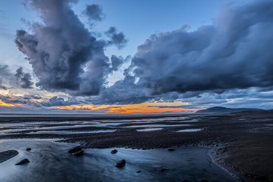 View of sunset over Black Combe from Walney Island with clouds and water reflections