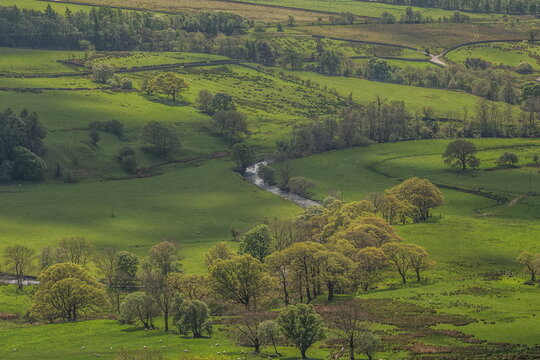 View from lower slopes of Blencathra showing the green fields and river in Lake District, Cumbria, United Kingdom during cloudy weather