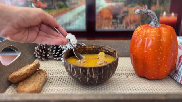 Cuchara tomando sopa de calabaza junto a la ventana