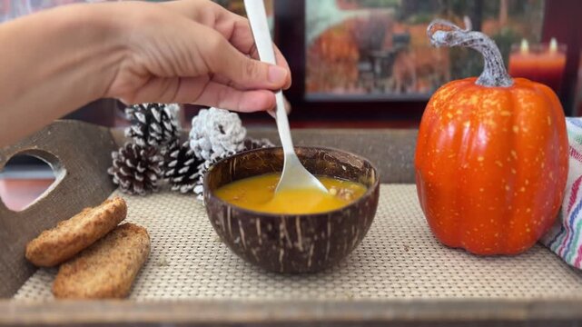 Mano removiendo sopa de calabaza junto a la ventana