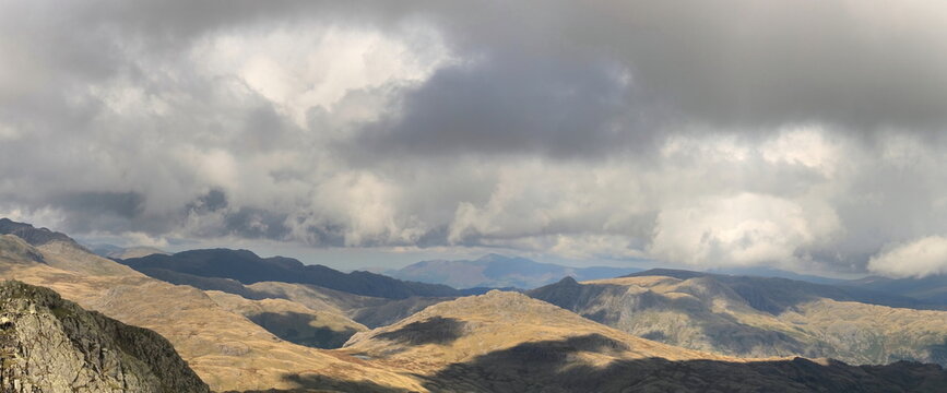 Shadows fall on Langdale Pikes and surrounding mountains in the Lake District from Coniston Old Man in Cumbria