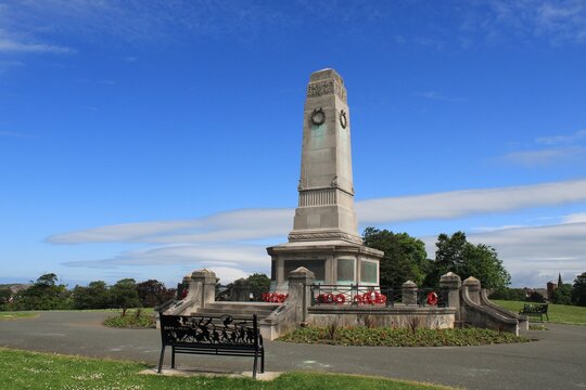 Barrow Park Cenotaph stands in remembrance of those who served in conflict, surrounded by green spaces and blue skies