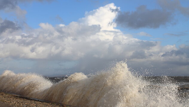 Breezy day at the Cumbrian Coast with crashing waves and a view towards Morecambe Bay in the United Kingdom