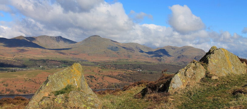 View across Coniston Water towards the mountain range of Coniston in the United Kingdom under changing sky conditions