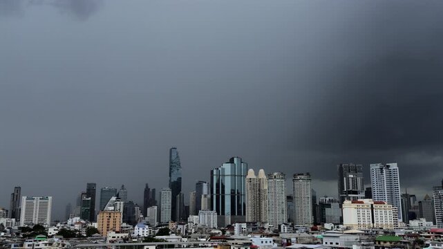 Timelapse of a stormy Bangkok cityscape beneath dense dark clouds before heavy rainfall.