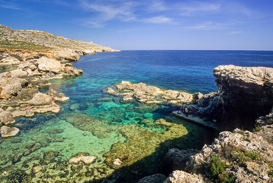 Clear water of a creek flows into the Mediterranean Sea at Ghar Lapsi in Malta under a bright blue sky