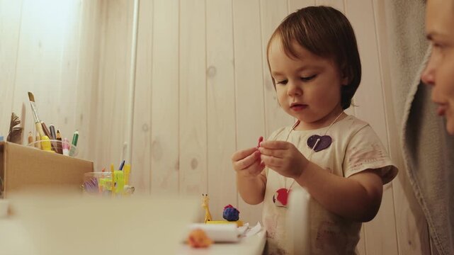 Toddler exploring colorful clay while spending a quiet afternoon in a cozy room with family nearby.