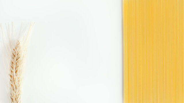 Wheat and uncooked spaghetti create a natural food frame around white copy space. Soft neutral tones suit culinary branding, recipe layouts, and commercial design.