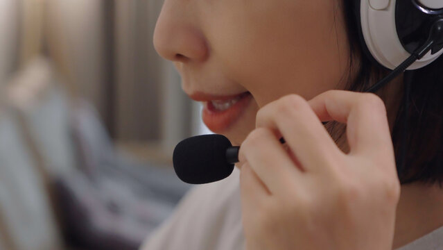 Close-up of a young woman wearing a headset microphone for online teaching, e-learning, video calls, and digital communication at home.