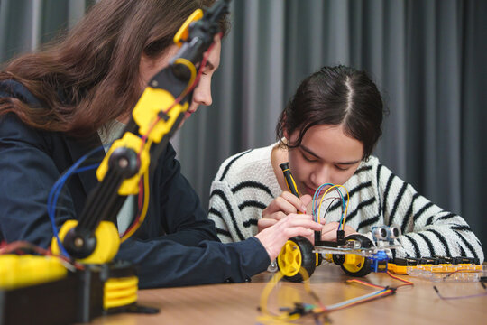 Teacher guiding a student assembling a robotics project in a STEM classroom, highlighting engineering skills, teamwork, innovation, and hands-on technology learning.