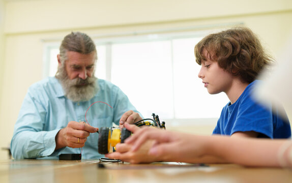 Teacher mentors a student assembling a STEM robotics project, building engineering knowledge, critical thinking, and hands-on technology skills in the classroom.
