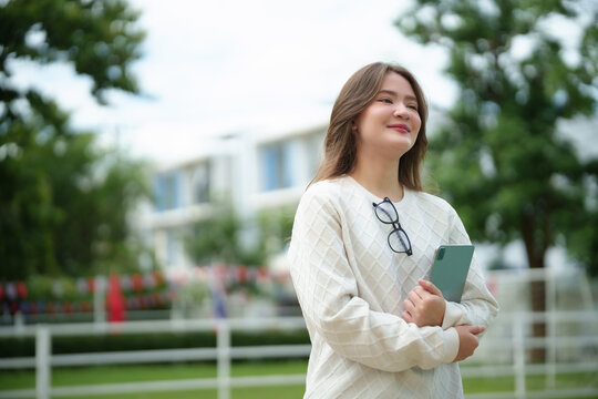 Smiling university student holding a digital tablet on campus, expressing confidence, academic success, and a positive lifestyle in a modern higher education environment.
