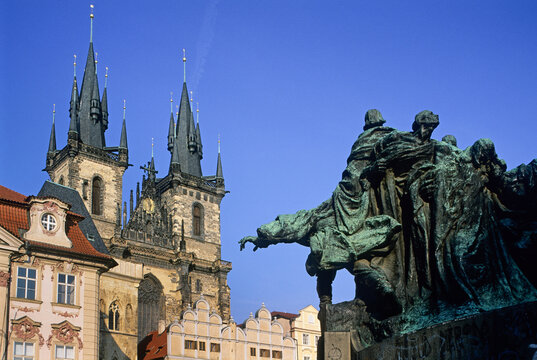 Jan Hus Monument stands in Old Town Square with Church of Our Lady before Tyn in background in Prague, Czech Republic