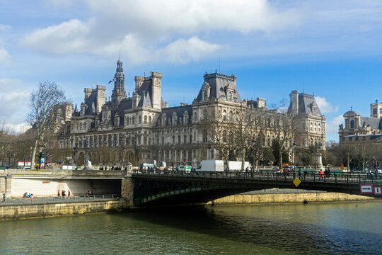 View of Hotel de Ville across the Seine River on a sunny winter day in Paris, France with clear blue sky and scattered clouds