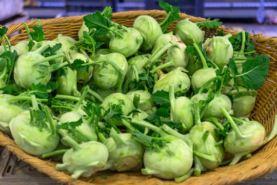Fresh kohlrabi placed carefully in a woven basket at a market in France during the harvest season
