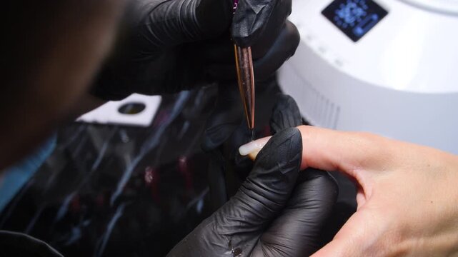 A woman's hand during a manicure. A woman getting a manicure. A manicurist is doing a client's nails at a nail salon. Beauty salon concept: manicures, pedicures.
