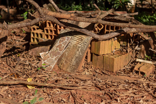 Pile of mud bricks, ceramic tiles, and dry branches on the soil