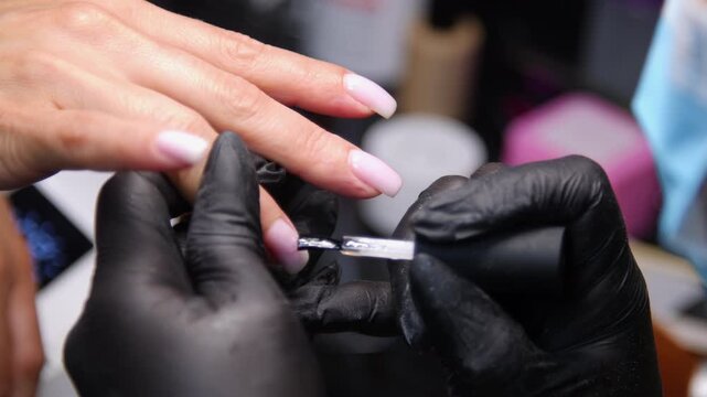 A woman's hand during a manicure. A woman getting a manicure. A manicurist is doing a client's nails at a nail salon. Beauty salon concept: manicures, pedicures.
