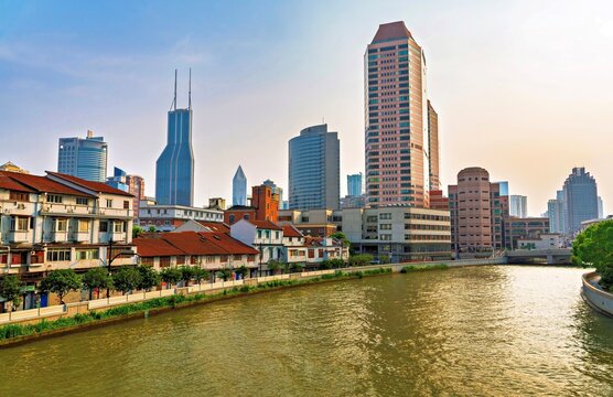 Suzhou Creek shows a mix of old and new buildings along its banks in Shanghai, China during sunset