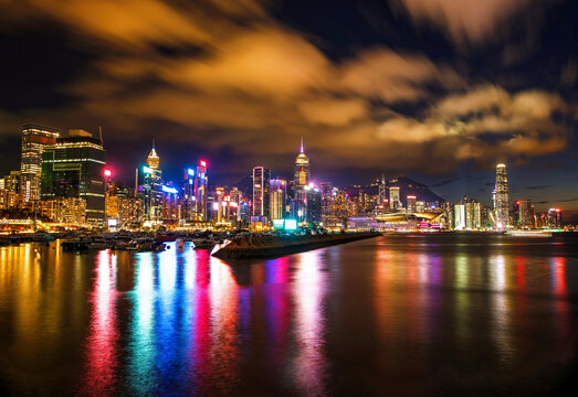 Night lights reflect on water as buildings brighten the Hong Kong skyline from a waterfront view in the evening hours
