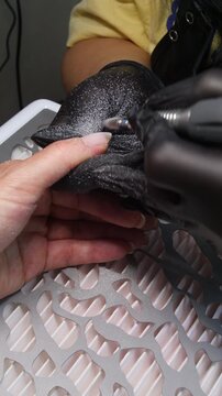 A woman's hand during a manicure. A woman getting a manicure. A manicurist is doing a client's nails at a nail salon. Beauty salon concept: manicures, pedicures.