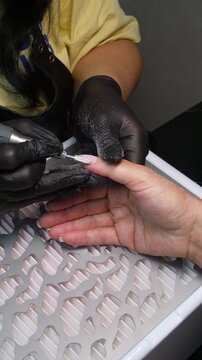 A woman's hand during a manicure. A woman getting a manicure. A manicurist is doing a client's nails at a nail salon. Manicure services - Vertical video