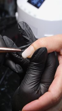 A woman's hand during a manicure. A woman getting a manicure. A manicurist is doing a client's nails at a nail salon. Manicure services - Vertical video