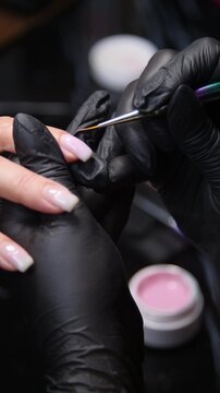A woman's hand during a manicure. A woman getting a manicure. A manicurist is doing a client's nails at a nail salon. Manicure services - Vertical video