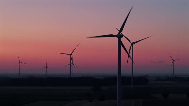 Wind turbines on a wind farm at dawn, rotating blades that convert wind into clean, renewable electricity.