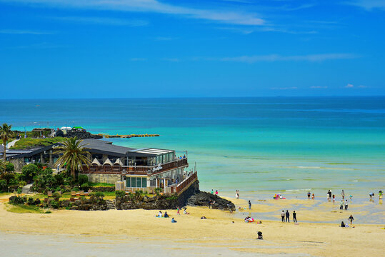 Visitors relax and enjoy activities at Hamdeok Beach on a sunny day in Jeju Island, South Korea