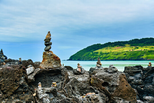 Stone stacks balance on rocks at Hamdeok Beach in Jeju Island South Korea during a cloudy day