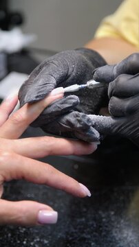 A woman's hand during a manicure. A woman getting a manicure. A manicurist is doing a client's nails at a nail salon. Manicure services - Vertical video