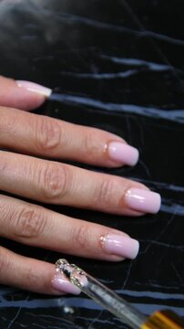 Receiving Professional Manicure in Modern Salon. Beautiful, well-groomed women's hands with elegant nails against a dark background. Beauty salon concept: manicures, pedicures - Vertival video