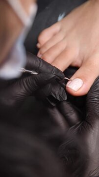 A woman's feet during a pedicure. Woman getting pedicure in beauty salon, closeup. A pedicurist working at a beauty salon. Beauty salon concept: pedicures - Vertical video