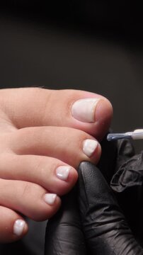 A woman's feet during a pedicure. Woman getting pedicure in beauty salon, closeup. A pedicurist working at a beauty salon. Beauty salon concept: pedicures - Vertical video