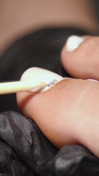 A woman's feet during a pedicure. Woman getting pedicure in beauty salon, closeup. A pedicurist working at a beauty salon. Beauty salon concept: pedicures - Vertical video