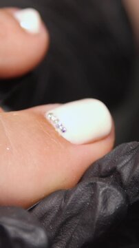 A woman's feet during a pedicure. Woman getting pedicure in beauty salon, closeup. A pedicurist working at a beauty salon. Beauty salon concept: pedicures - Vertical video