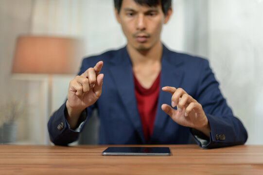Businessman gesturing towards smartphone at desk in modern office setting