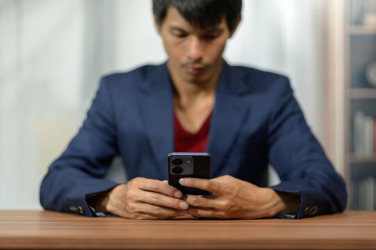 Young Man Using Smartphone at Desk in Modern Indoor Environment