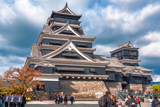 Kumamoto Castle stands tall against a backdrop of autumn colors during a busy day in Kumamoto City, Kyushu, Japan