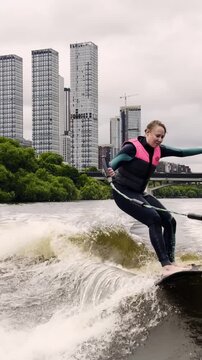 Energizing wake surfing session on a river near city buildings with a clear view of the skyline