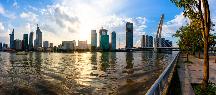 Saigon River promenade features urban skyline at sunset in Ho Chi Minh City Vietnam